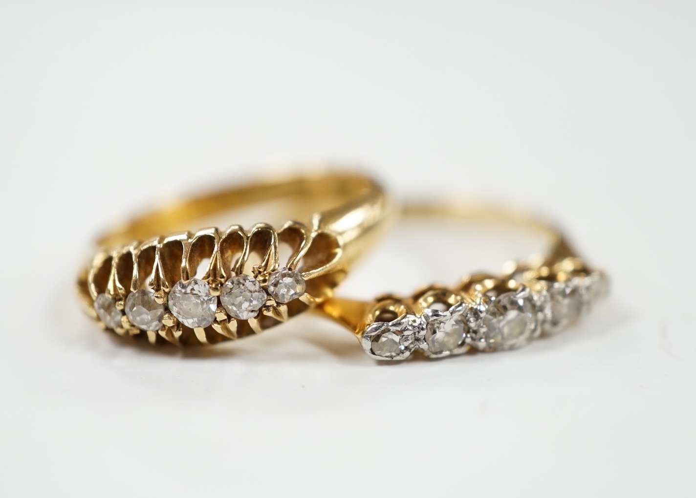 Two early 20th century 18ct gold and graduated five stone diamond set half hoop rings